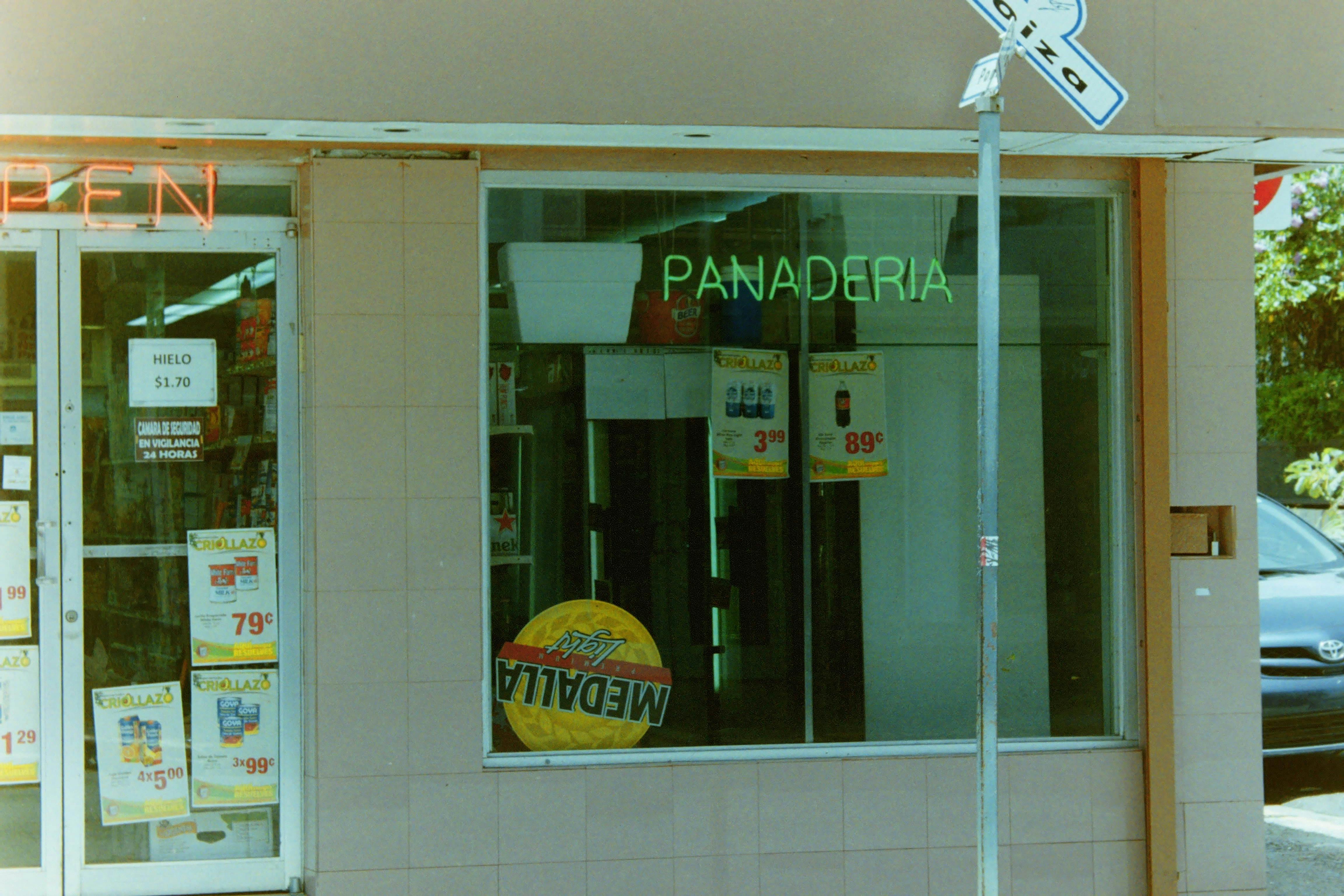A bakery store front displaying neon signs and advertisements.