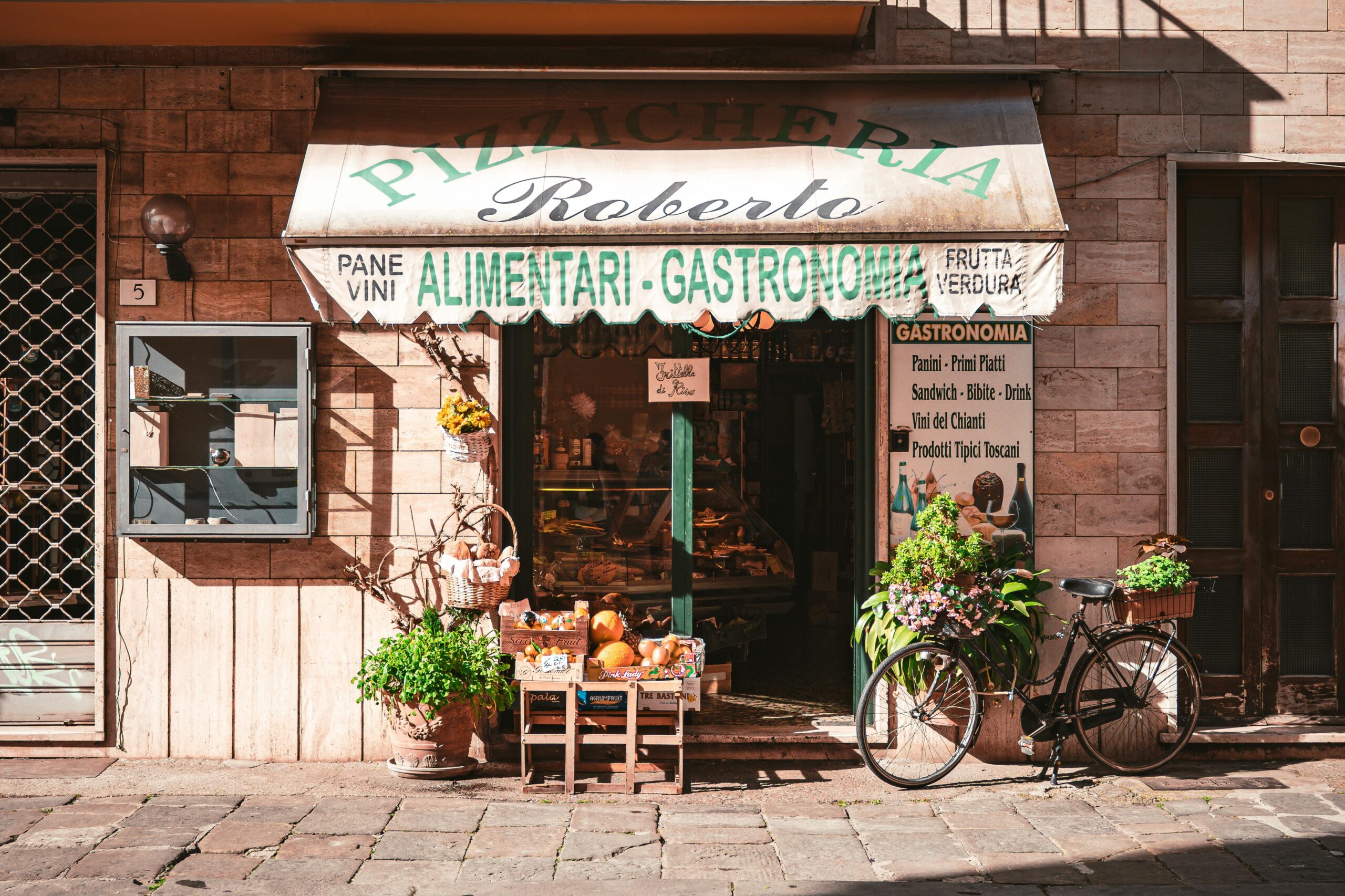 A quaint Italian grocery store with fresh produce and a vintage bicycle outside, offering local delicacies.