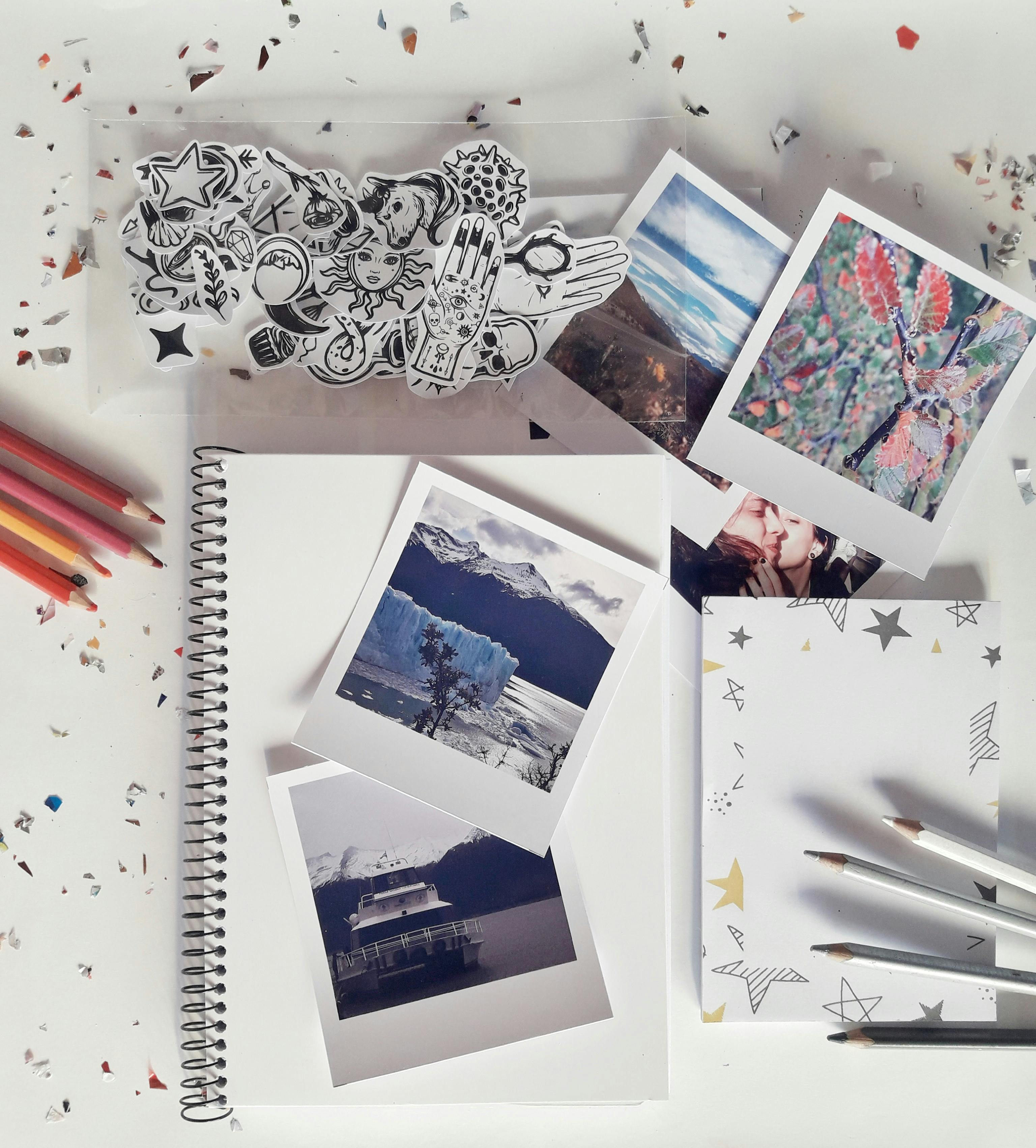 Flat lay of a creative desk setup with photos, notebook, and stationery for artistic inspiration.